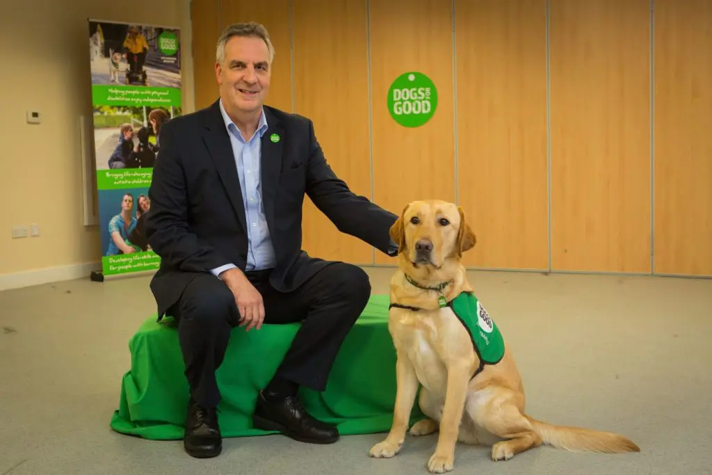 Dogs for Good CEO Peter Gorbing with his hand on the shoulder of an assistance dog