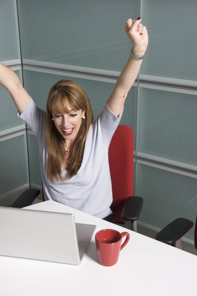 Woman on an office chair raising her hands in joy