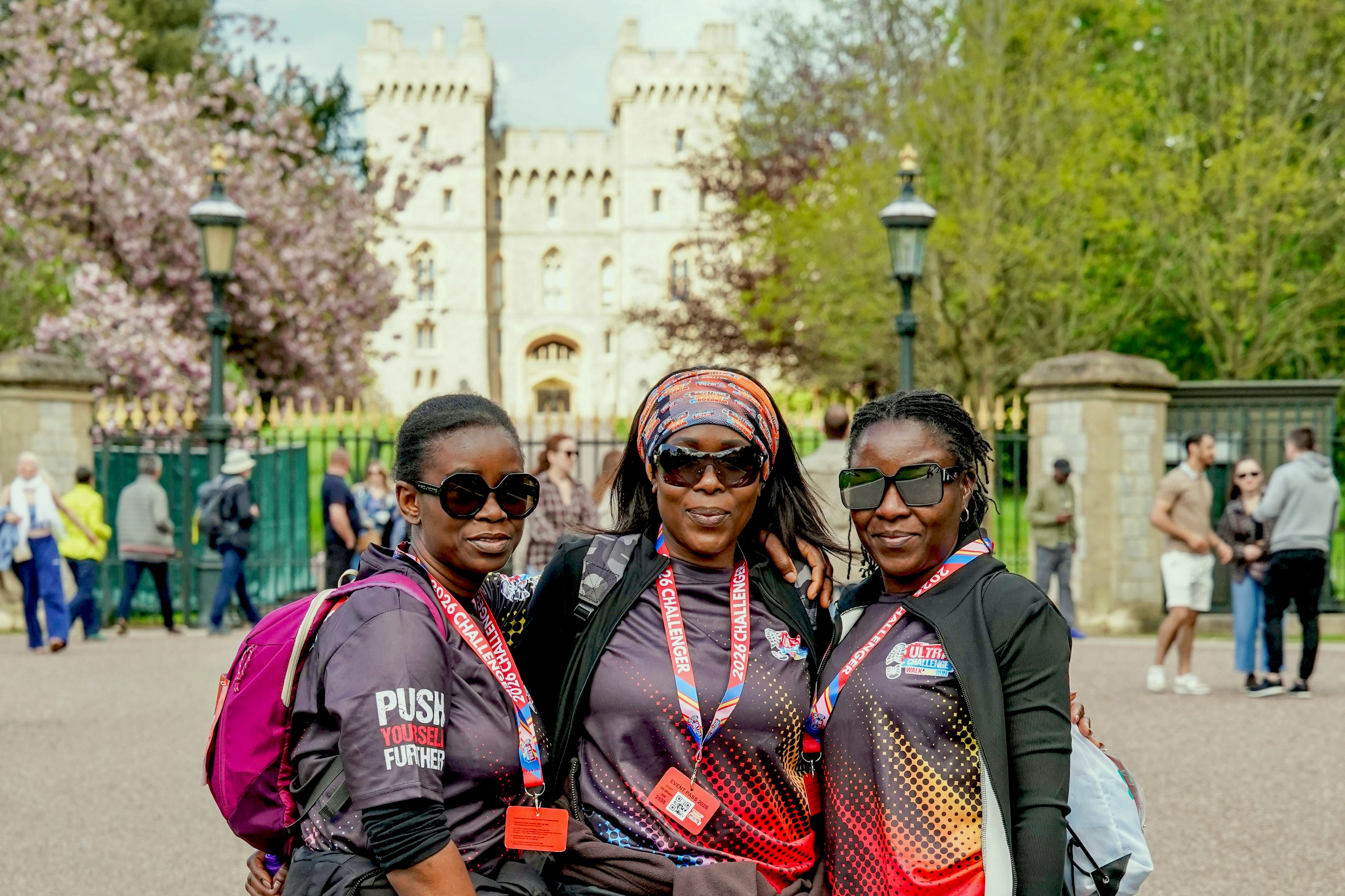 Three Windsor 50 Ultra Challenge participants wearing sunglasses and lanyards standing outside of Windsor Castle