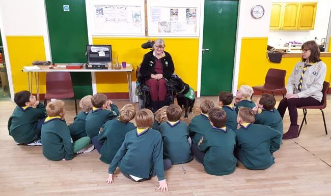 Lady in wheelchair with assistance dog talking to Cubs pack