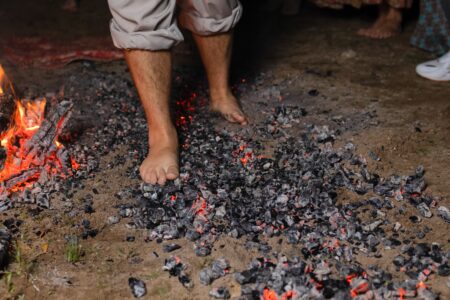 Bare feet walking on hot coals next to a fire